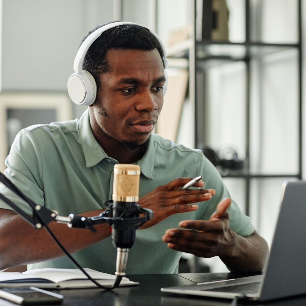 Homem negro grava um podcast com fone de ouvido diante do microfone